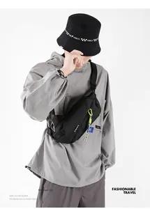 Close-up of black nylon crossbody bag with green pull tabs worn by a model in casual style
