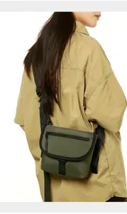 Detail view of olive green nylon crossbody bag showing the adjustable black strap and flap