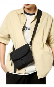 Detail of black nylon crossbody bag featuring a curved flap and buckle closure for commuters