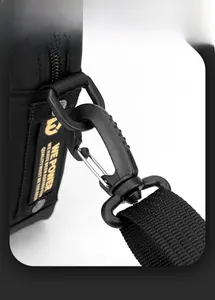 Detail shot of heavy-duty matte carabiner hook and brand label on black nylon shoulder bag