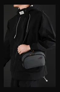 Dettaglio borsa tech in nylon grigio scuro con doppia cerniera e dettagli arancio