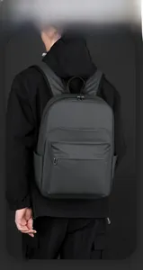 Man wearing a dark gray business backpack with smart storage space in a studio setting