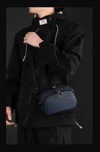 Dettaglio della borsa a tracolla blu navy con tessuto strutturato e tiretti arancioni