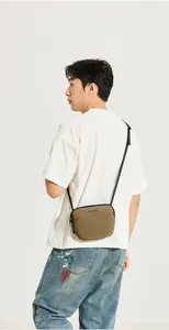Vue latérale d'un sac bandoulière léger kaki porté par un mannequin homme stylé