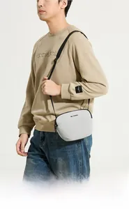 Gros plan sur le sac bandoulière minimaliste en nylon gris clair montrant le logo