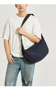 Dettaglio della borsa a tracolla blu navy con ampia fascia nera ed etichetta arancione