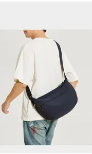 Détail du grand sac bandoulière en nylon bleu marine avec accents orange et sangle
