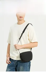 Détail d'un sac bandoulière noir léger avec logo embossé et sangle réglable en tissu