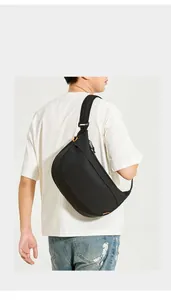 Détail du sac bandoulière en nylon noir imperméable avec accents orange sur un mannequin