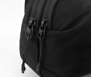 Détail du sac bandoulière en nylon noir avec double fermeture éclair et cordons tissés