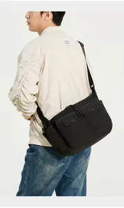 Side view of a black tactical crossbody bag with dual flap pockets and wide shoulder strap