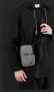 Détail d'un sac bandoulière gris en nylon avec fermeture éclair et rabat de marque