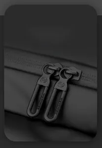 Dettaglio di cerniere nere con logo inciso su una borsa a tracolla sportiva tecnica