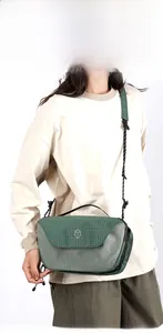 Detail of green checkered crossbody bag featuring adjustable strap and hexagonal logo