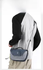 Close-up of navy plaid fabric and grey mesh crossbody bag with paracord strap detail