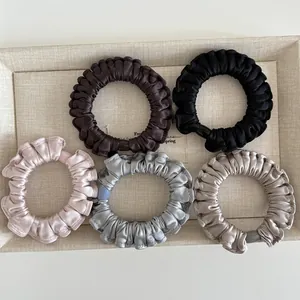 Detailed view of satin ruffled hair scrunchies in coffee, pink, and champagne tones