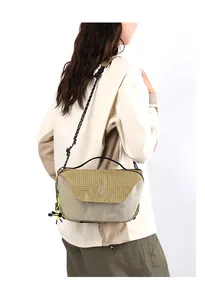 Detail of a khaki crossbody bag with textured fabric and braided rope strap on model