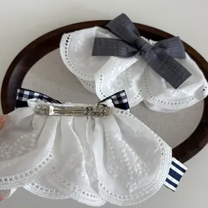 Macro detail of checkered and lace bow hair clips with metal spring clips on wood tray