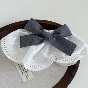 Detailed view of white floral lace hair clip with a grey plaid bow and embroidery