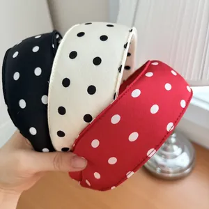 Close-up of three wide polka dot sponge headbands in black, white and red colors