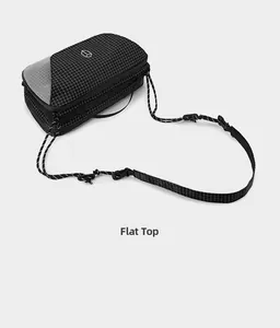 Flat lay top view of a black and white grid patterned crossbody bag with woven rope strap