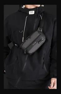 Close-up of waterproof nylon material and metal zippers on a dark gray techwear chest bag