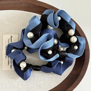 Detail of blue denim fabric scrunchies with white pearl accents and pleated texture