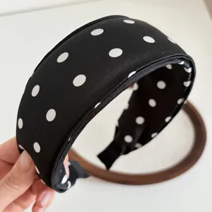 Detail of wide sponge headband with white polka dots on smooth black silk fabric