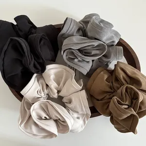Detailed macro view of four large fabric hair scrunchies in neutral earth tones on wood