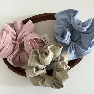 Three-piece set of large fabric scrunchies in pastel pink, blue, and beige colors