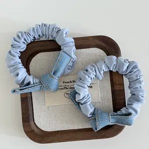 Detail of light blue denim knotted bow hair scrunchies on a wooden display tray