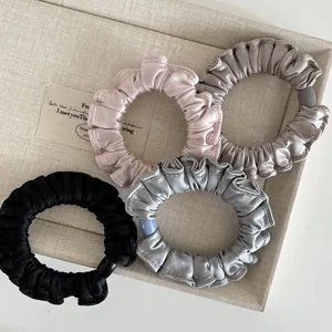Set of four satin pleated hair scrunchies in neutral tones with elegant round buckles