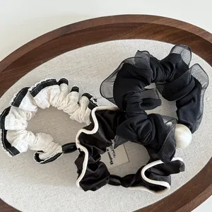 Detailed shot of three hair scrunchies with mesh lace and pearls in a wooden tray