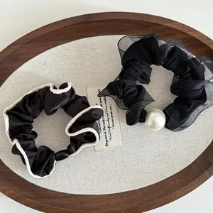 Detail view of black organza hair scrunchie with white pearl and satin lace trim