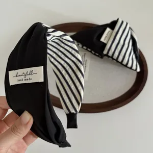Détail d'un serre-tête fait main en tissu à rayures noir et blanc avec étiquette tissée