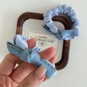 Light blue denim bow scrunchies with orange stitching in a French minimalist style