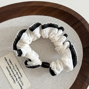 Close-up of elegant white mesh hair scrunchie with lace edges and black detail on linen