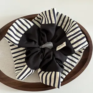 Détail d'un chouchou à rayures bleues et noir avec étiquette artisanale sur plateau bois