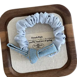 Light blue denim knotted bow scrunchie with white polka dots and orange stitching