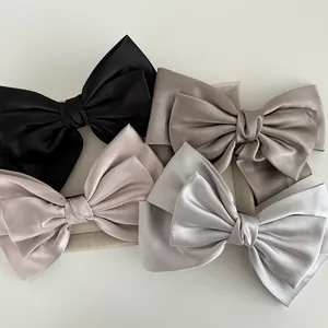 Detail showing the smooth satin texture and elegant drape of four colors of bow hair clips