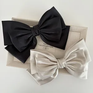 Detail of elegant black and champagne satin layered bow clips with silky texture