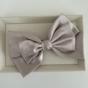 Close-up of the champagne satin bow hair clip showing elegant silky fabric texture