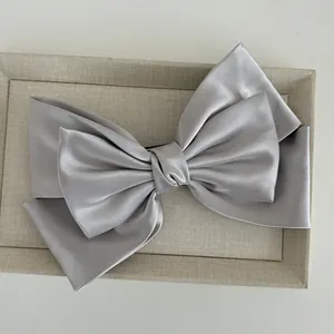 Detailed view of large silver grey satin bow hair clip with elegant layered silk texture