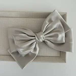 Detail of multi-layered champagne satin bow hair clip with elegant silk texture