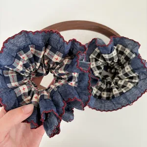Detail of navy denim and plaid scrunchies with red zigzag stitching and embroidery