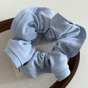 Light blue vintage ruffled fabric scrunchie with woven label in a wooden tray