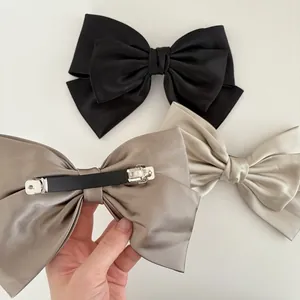 Three-piece satin bow hair clips set in black, champagne, and cream with metal spring clips