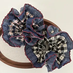 Navy blue denim and plaid scrunchie with red scalloped edges in a wooden bowl