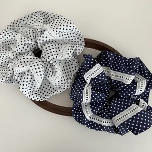 Detail von großen marineblauen und weißen Polka-Dot-Scrunchies mit weißer Spitzenkante