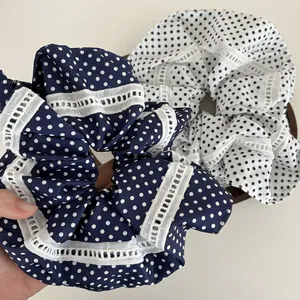 Nahaufnahme von dunkelblauen und weißen Polka-Dot-Haargummis mit feinen Spitzenrändern